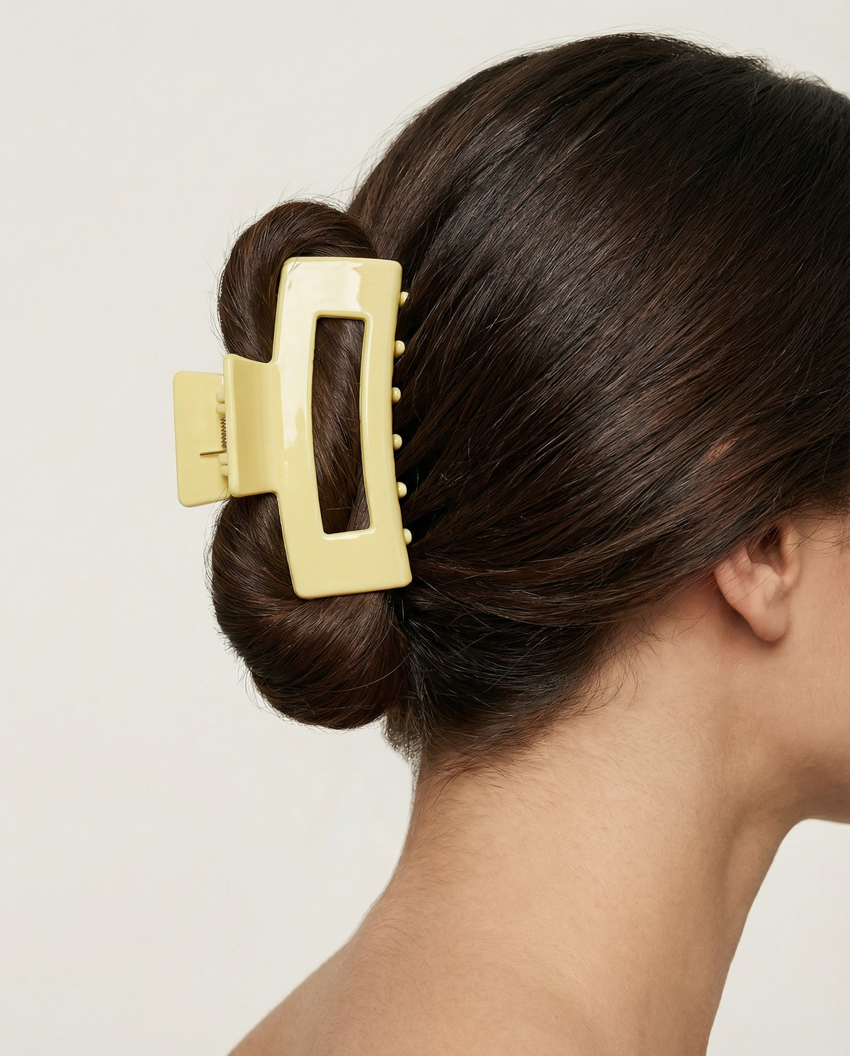 Yellow hair clip in a bun on a neutral background