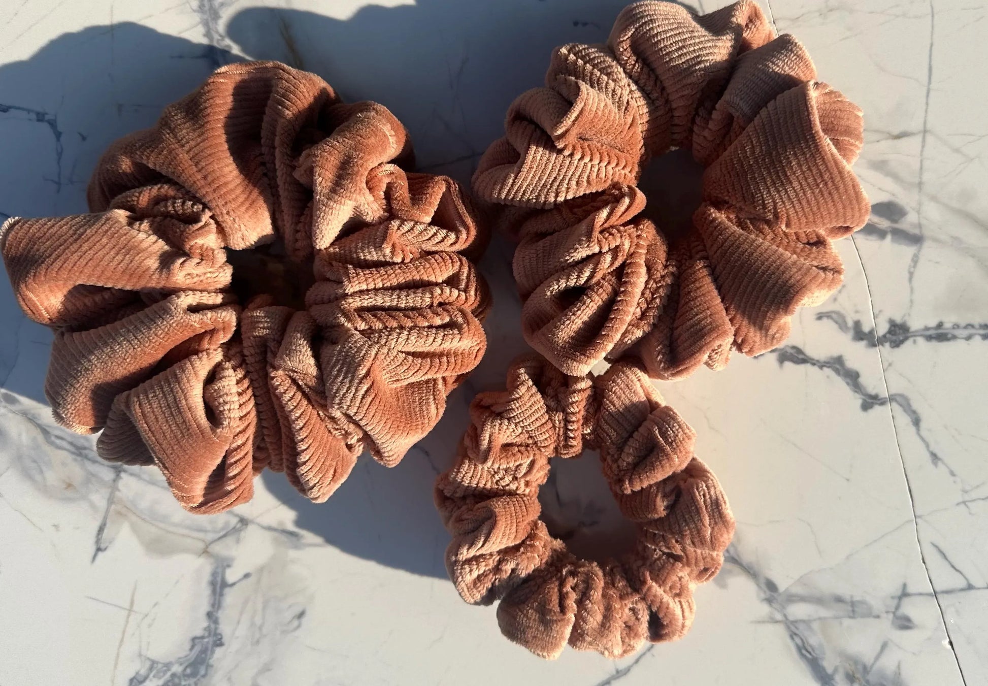 Three brown scrunchies on a marble surface